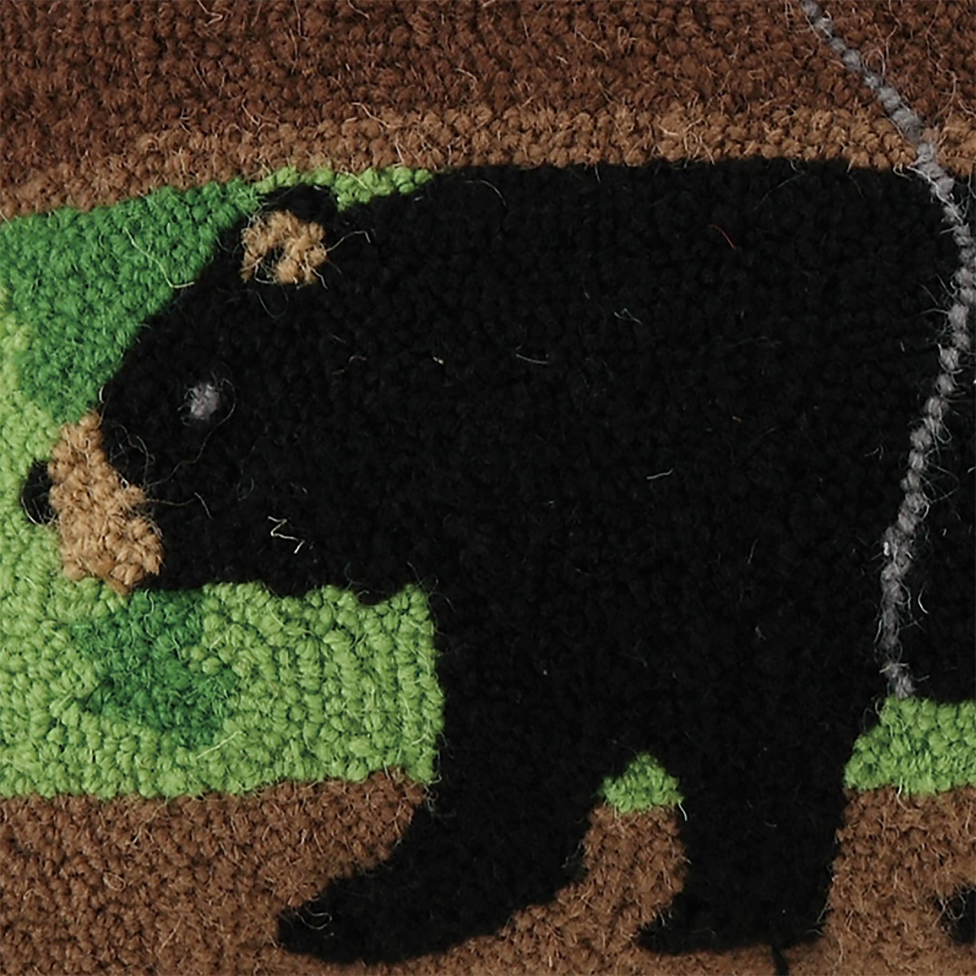 Doormat with a black bear design on a green patch, featuring natural textures.