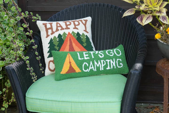 Green cushioned chair with 'Happy Campers' and 'Let's Go Camping' pillows.
