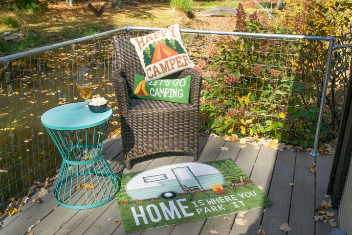 Chair with camping-themed pillows and rug on a deck with outdoor view
