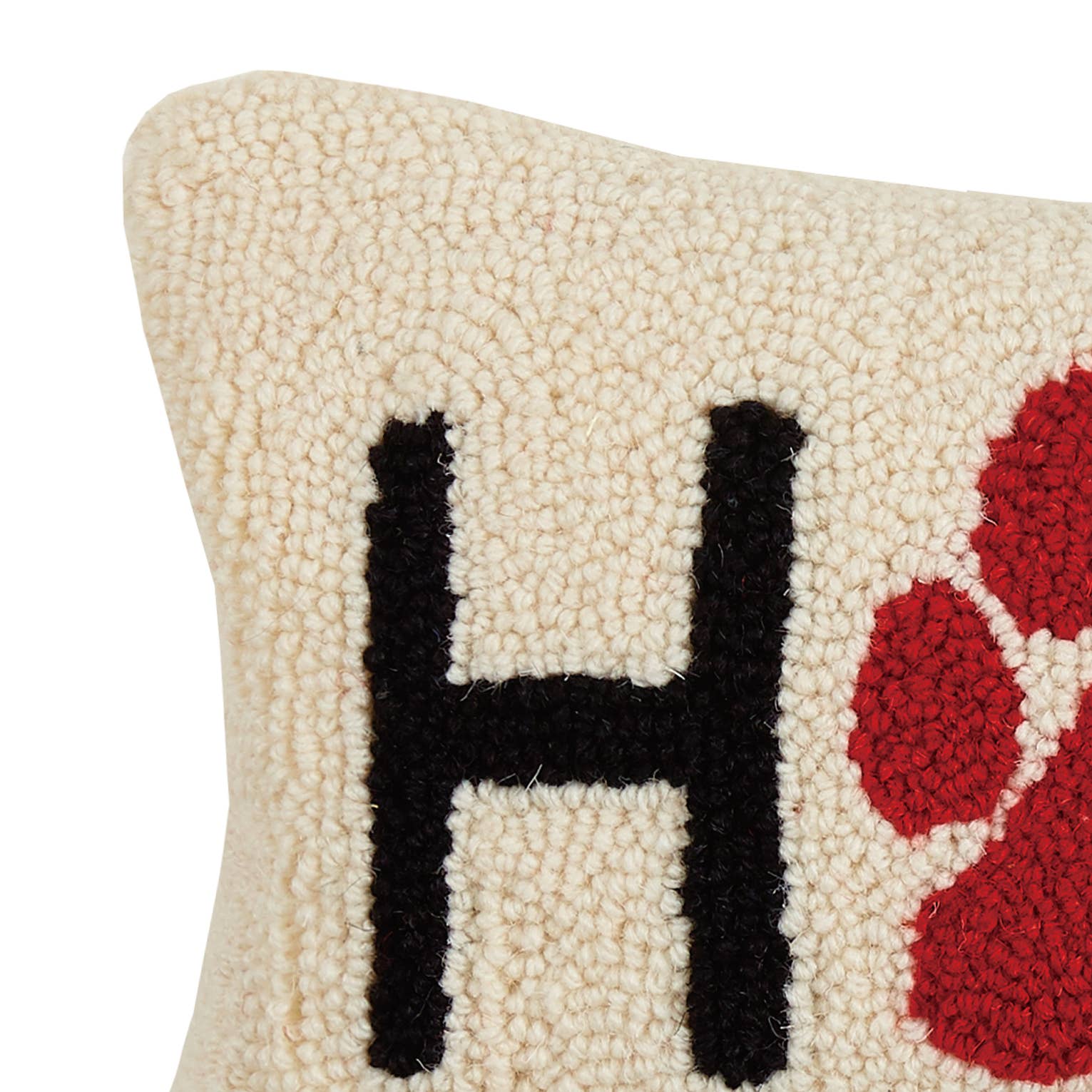 Textured pillow with a black 'H' and red floral design on a beige background
