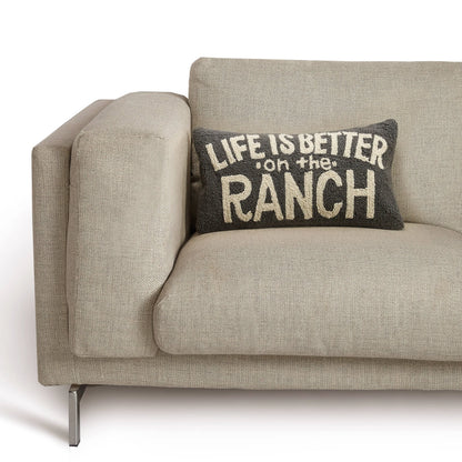 Beige sofa with a decorative pillow that reads 'Life is better on the ranch' on a white background