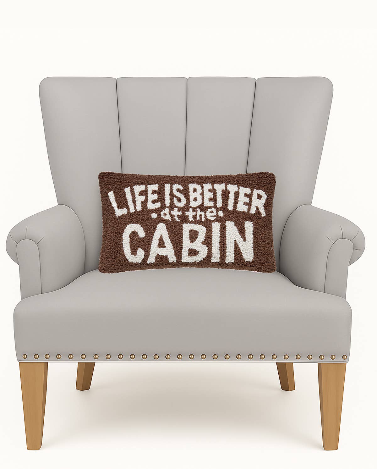Gray armchair with a brown pillow that says 'Life is better at the cabin' on a white background