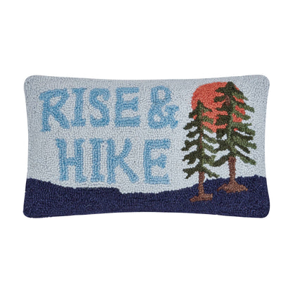 Decorative pillow with 'Rise & Hike' text and mountain design on a white background