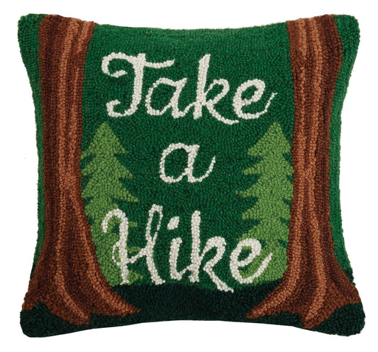 Decorative pillow with 'Take a Hike' text and forest design on a green background
