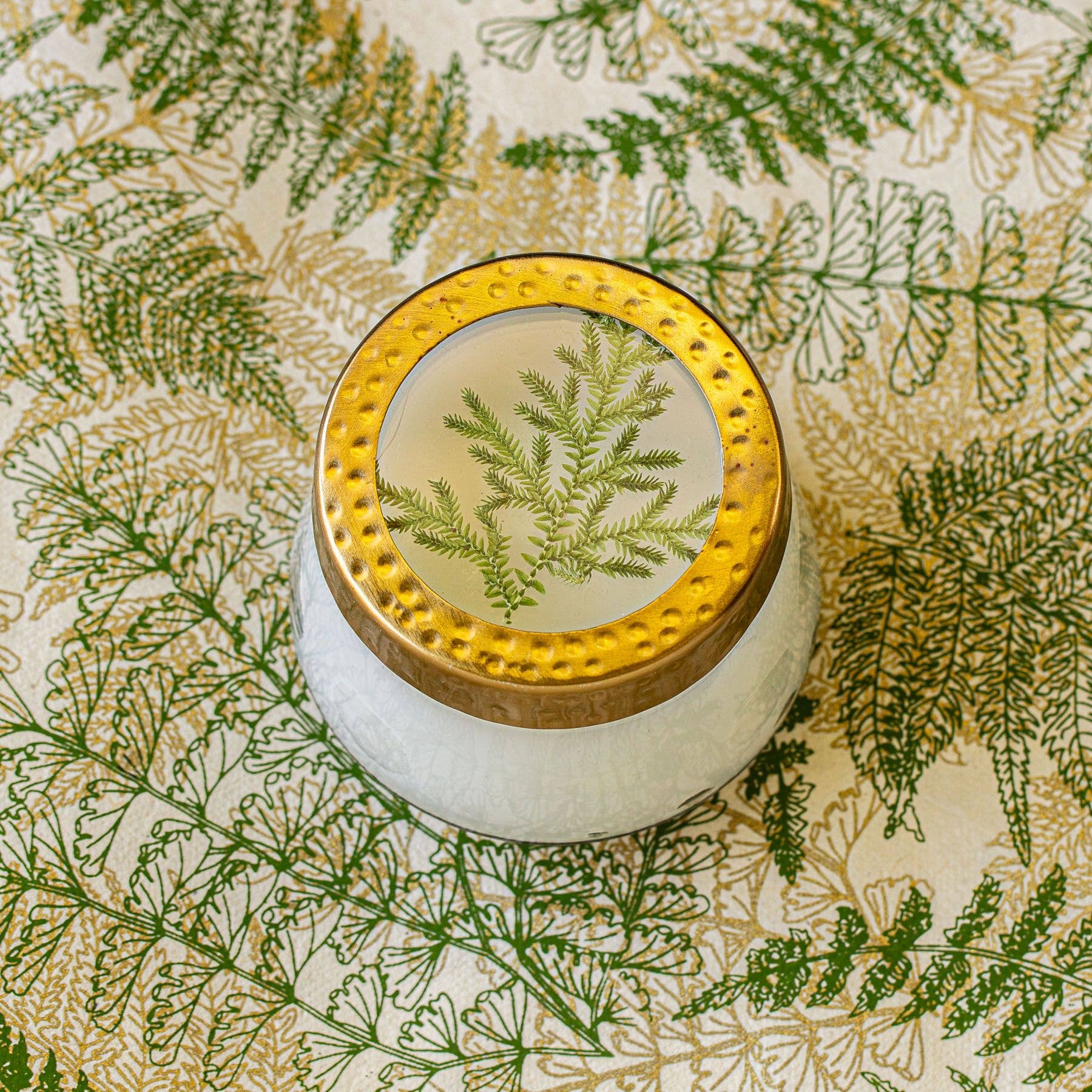 Decorative container with gold lid on a leaf-patterned background
