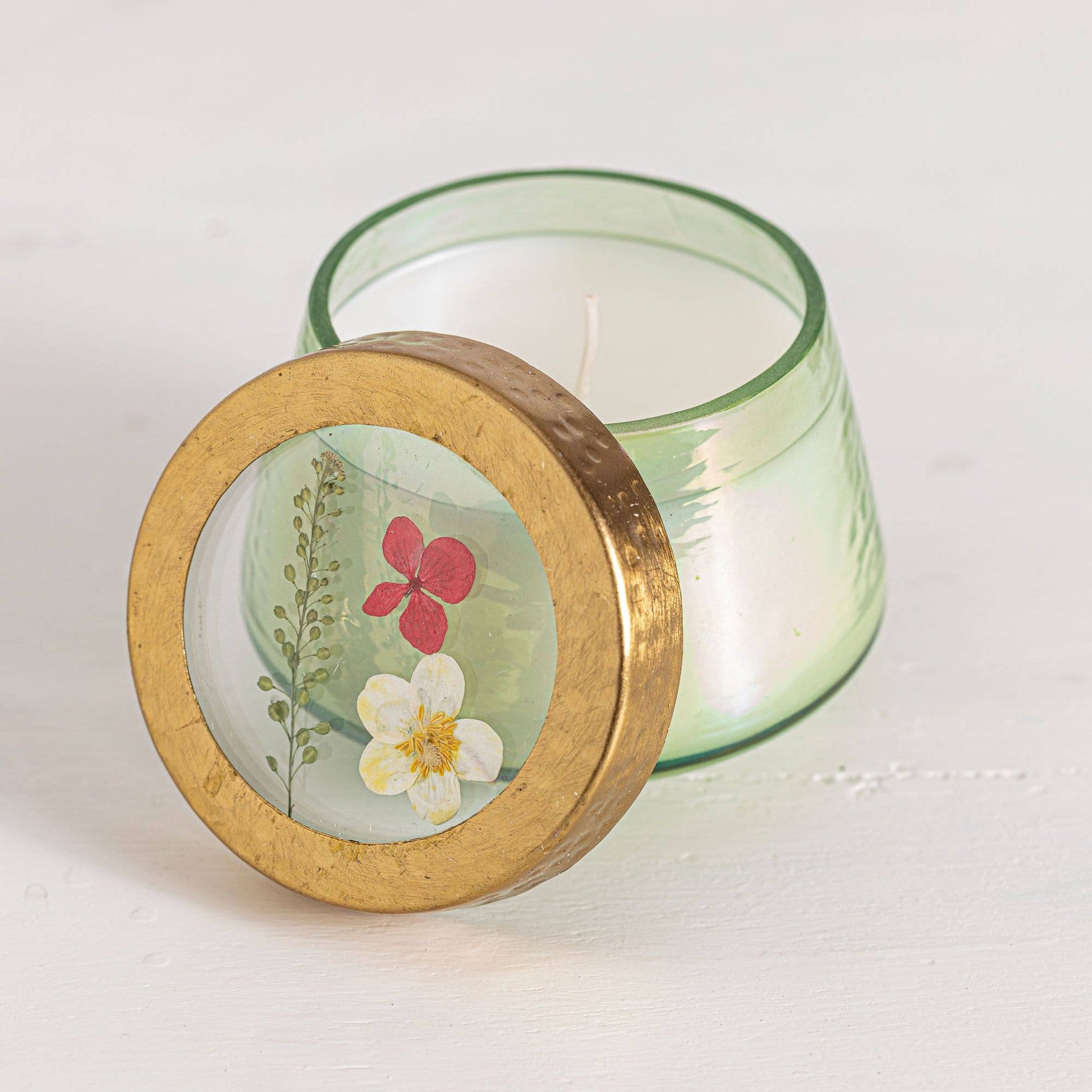 Candle with a decorative wooden lid featuring floral designs on a white background