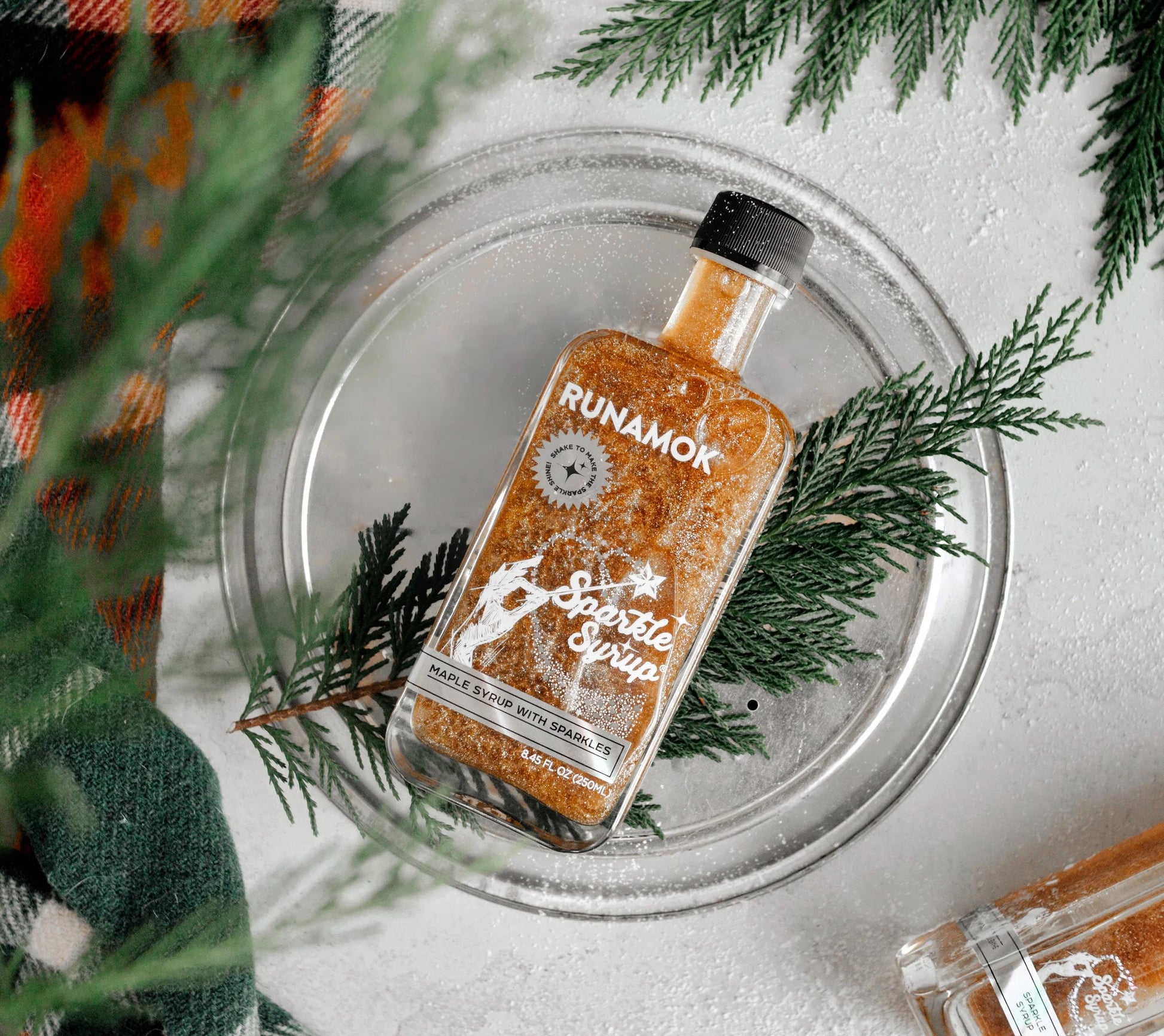 Bottle of Runamok Spiced Sprits on a glass coaster with greenery