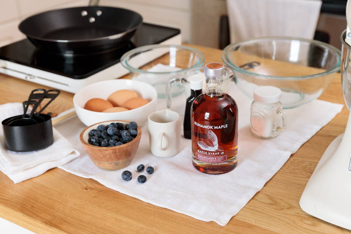 Table with ingredients and a bottle of syrup on a kitchen counter