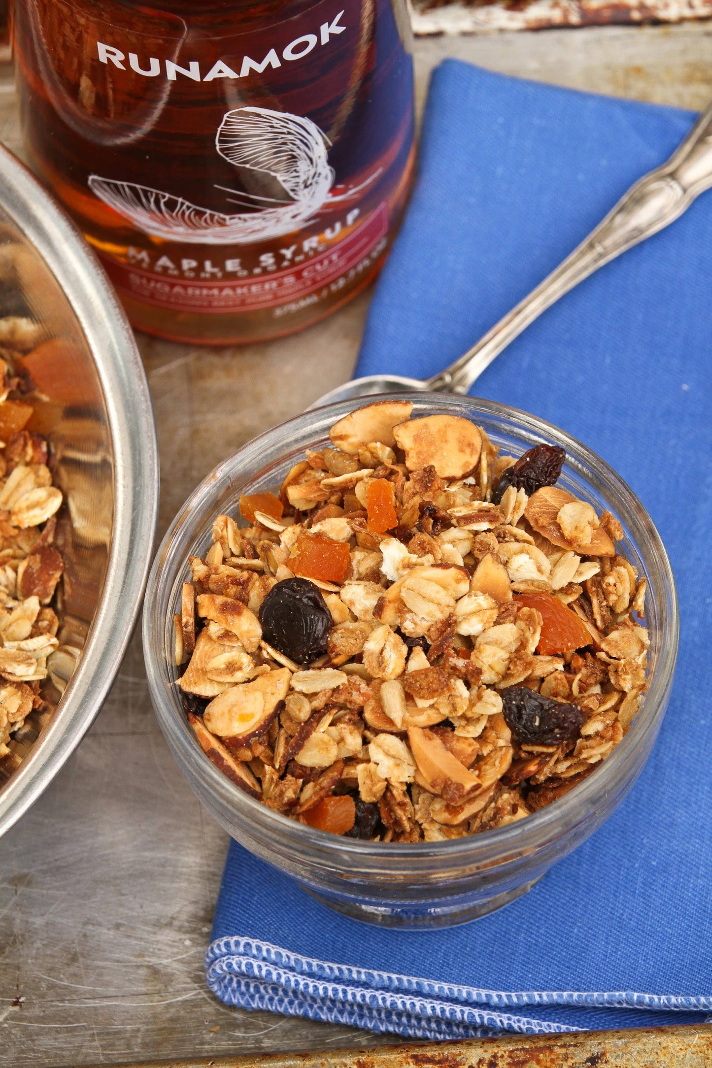 Glass bowl of granola with Runamok maple syrup in the background