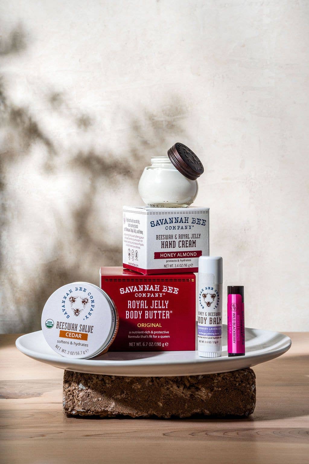 Collection of Savannah Bee Company products on a wooden surface with a blurred natural background