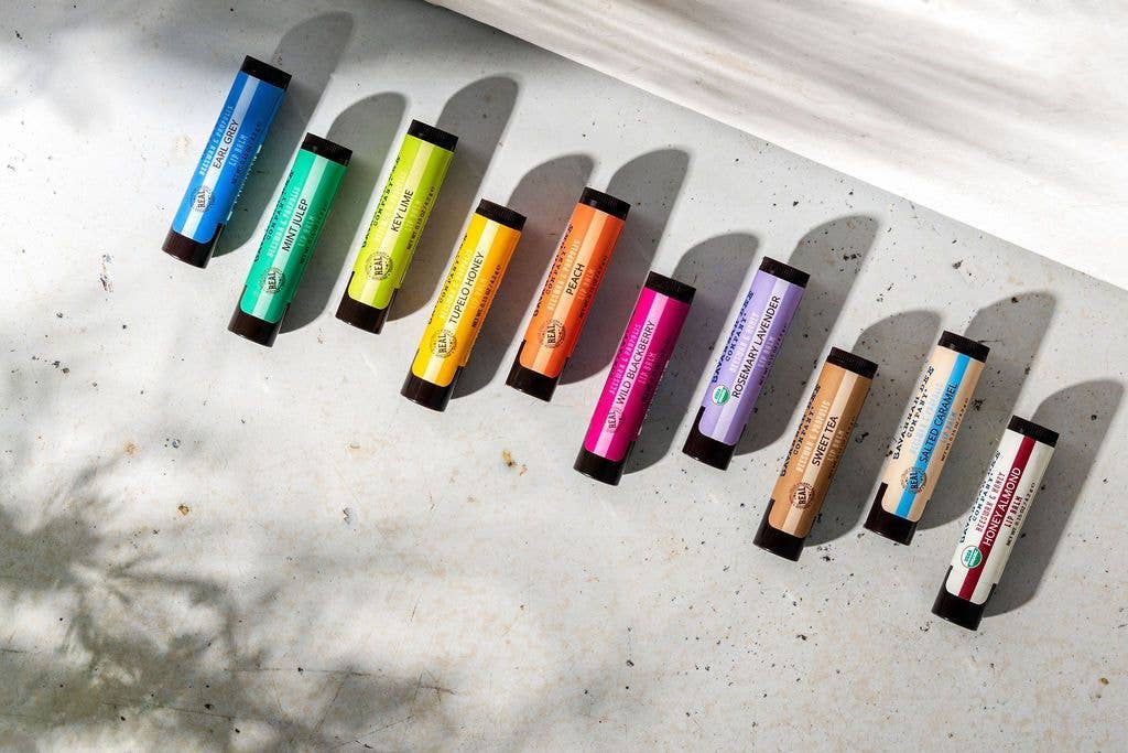 Row of colorful lip balms on a textured surface