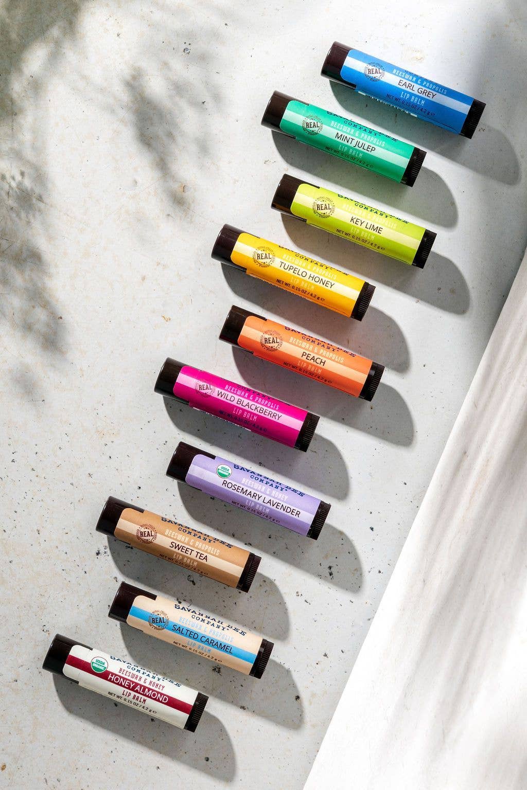 Row of colorful lip balm tubes on a textured surface