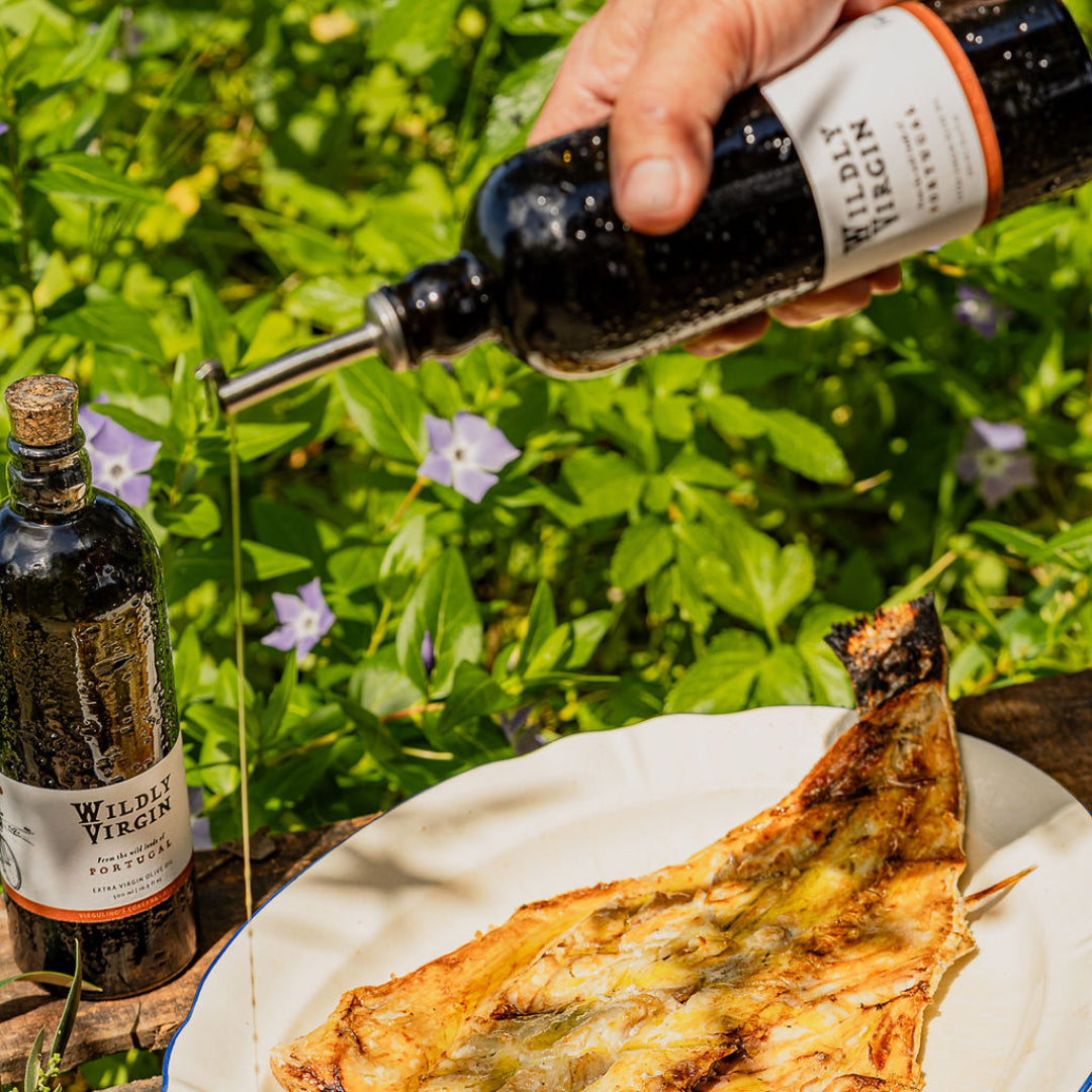 Person pouring Wildly Virgin syrup over a dish outdoors with greenery in the background