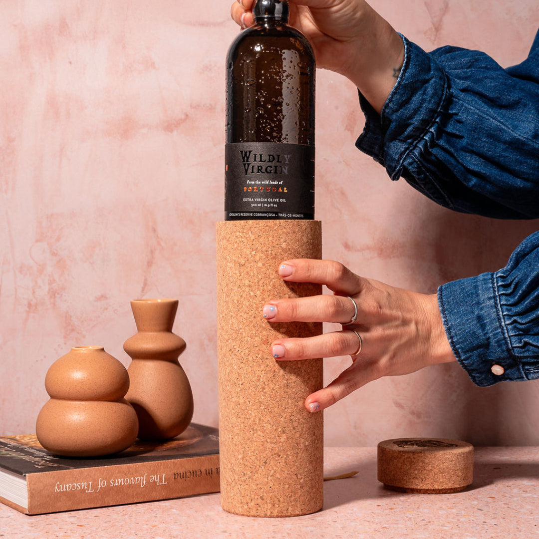 Person holding a bottle with a cork sleeve against a pink background