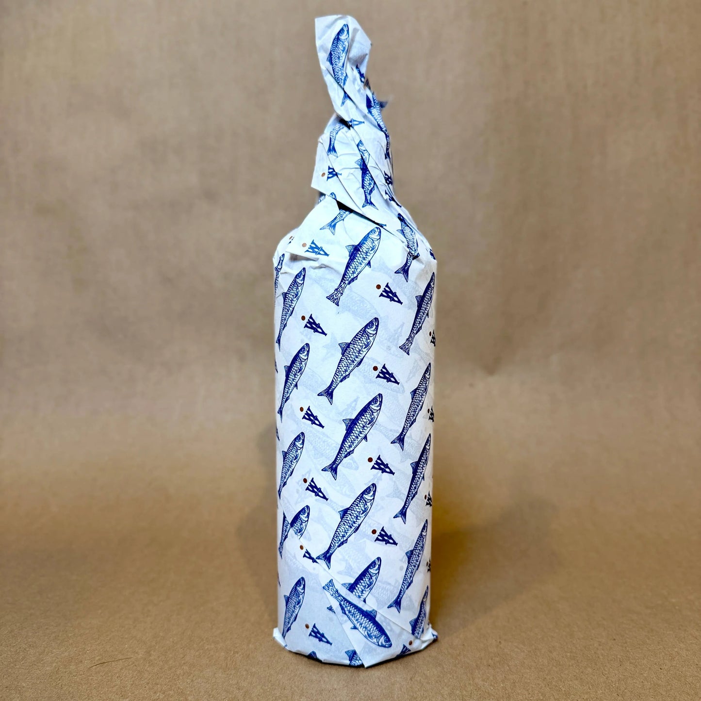 Bottle wrapped in white paper with blue whale pattern on a brown background